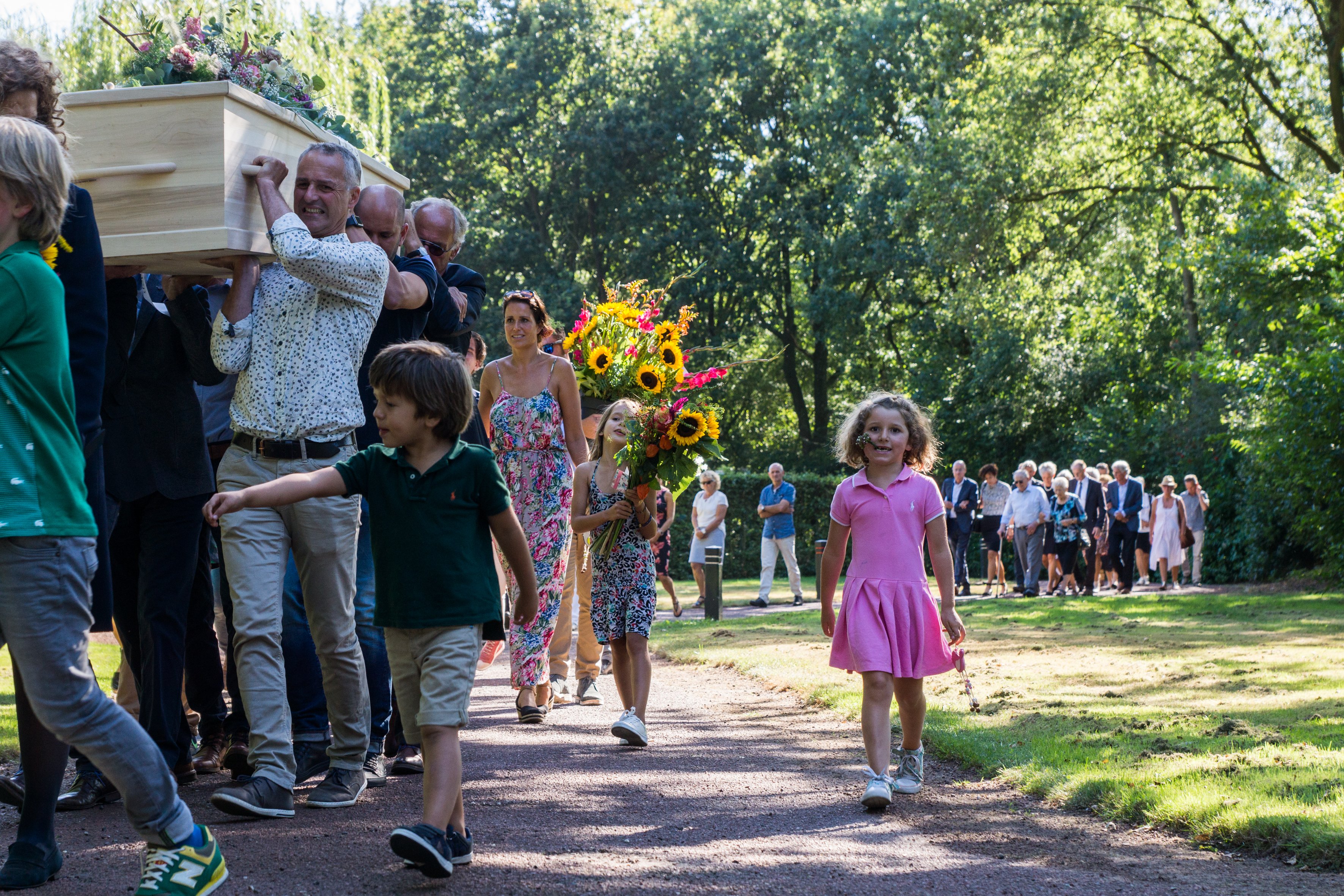 Naasten dragen samen de kist tijdens een uitvaartstoet